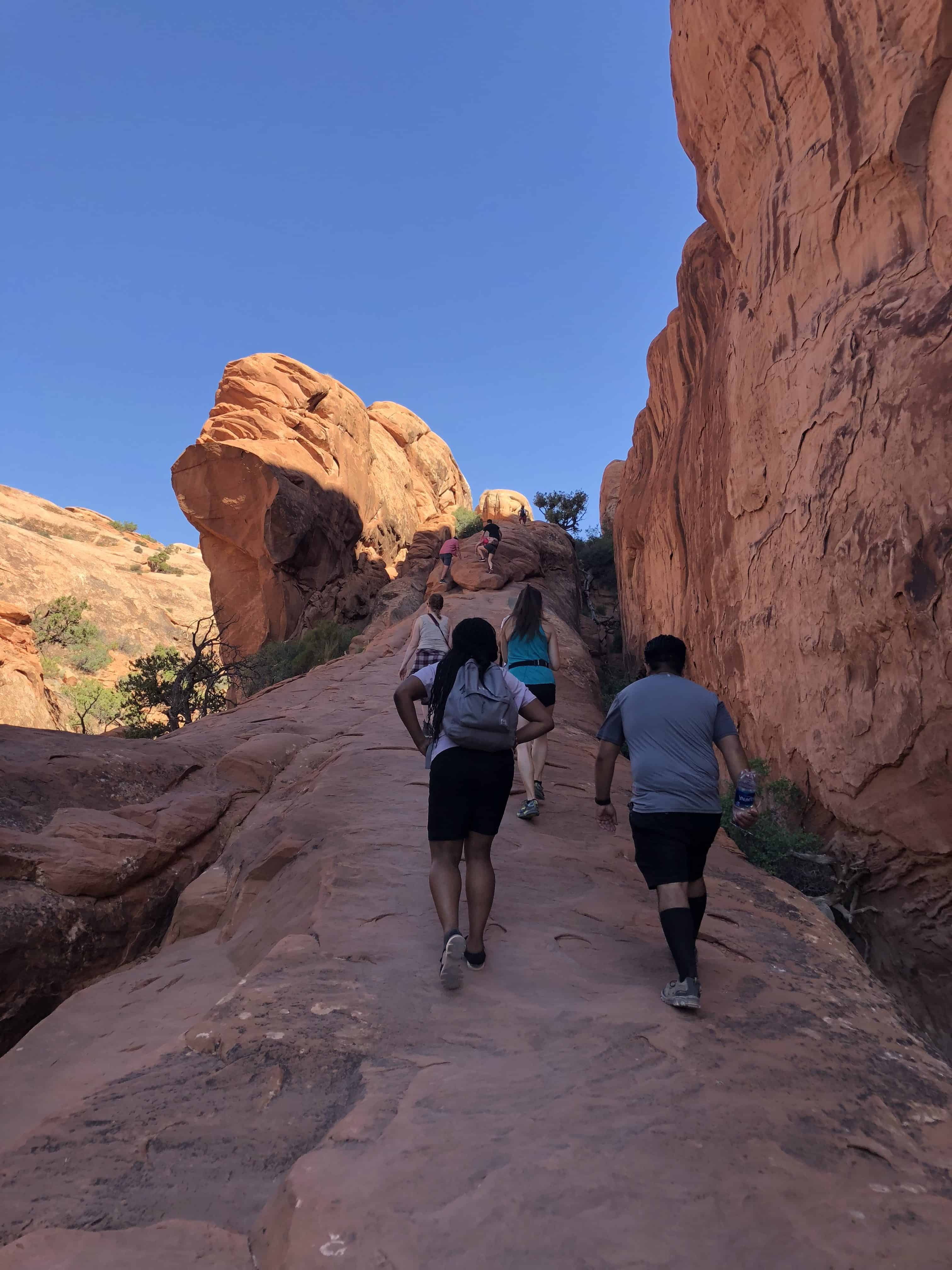 A group of people walking up a steep rocky section on the Devil's Garden Trail.