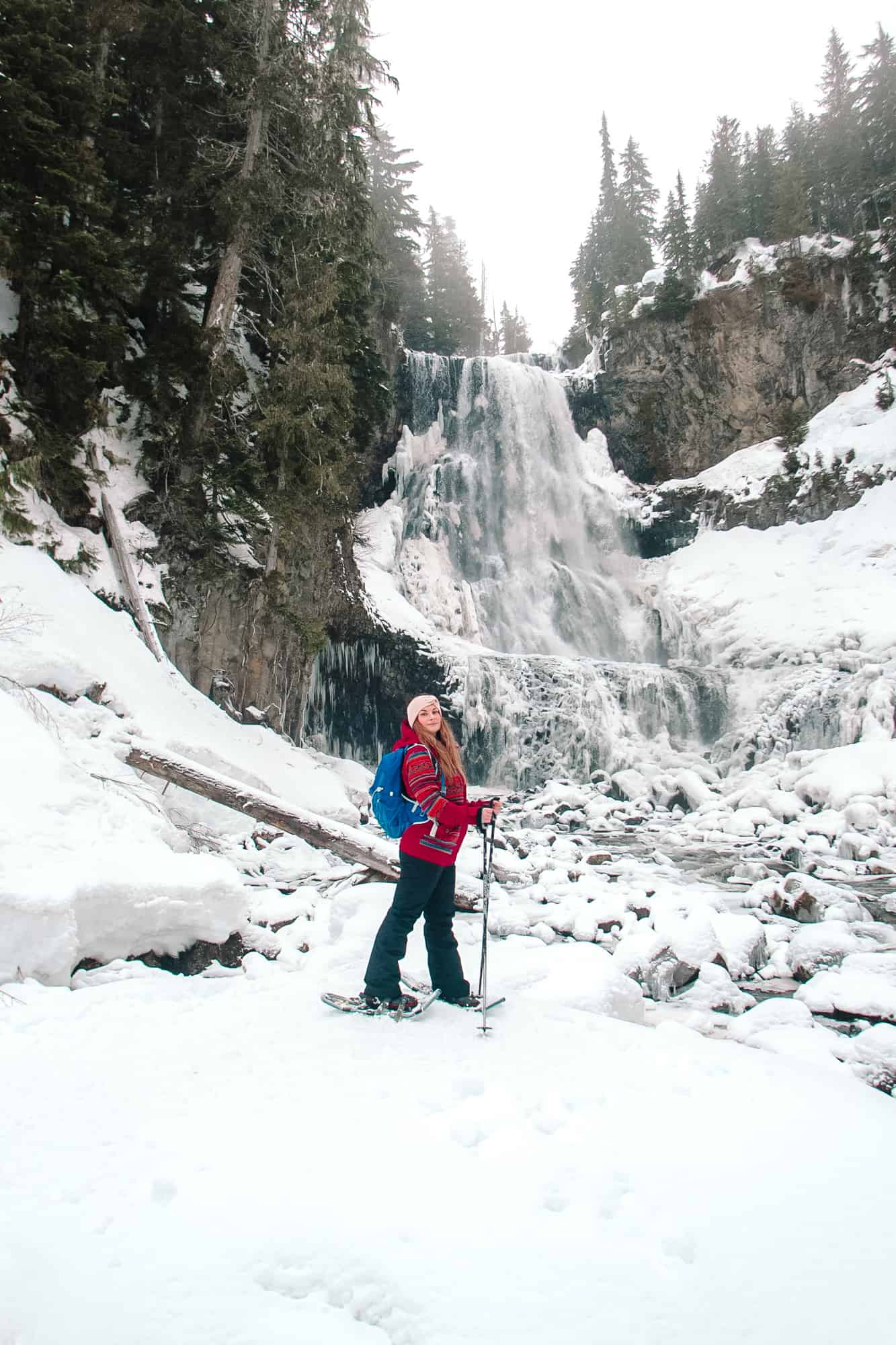 Rachael standing at the base of Alexander Falls, surrounded by snow in winter. Snowshoeing is one of the best free things to do in Whistler in winter.