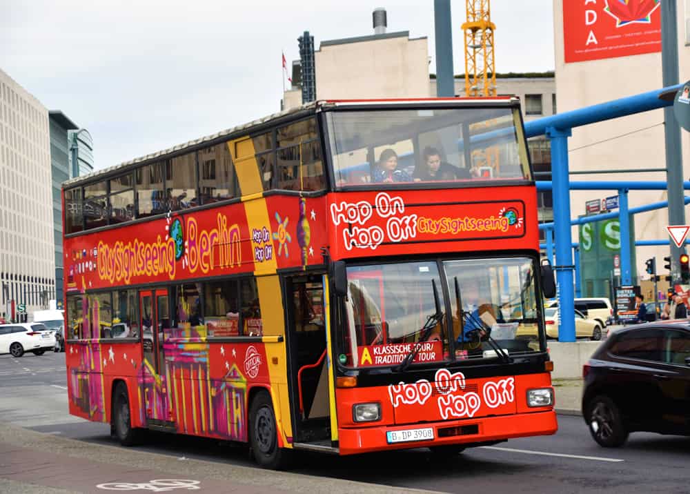 A double decker red bus driving through a city with passengers on board.
