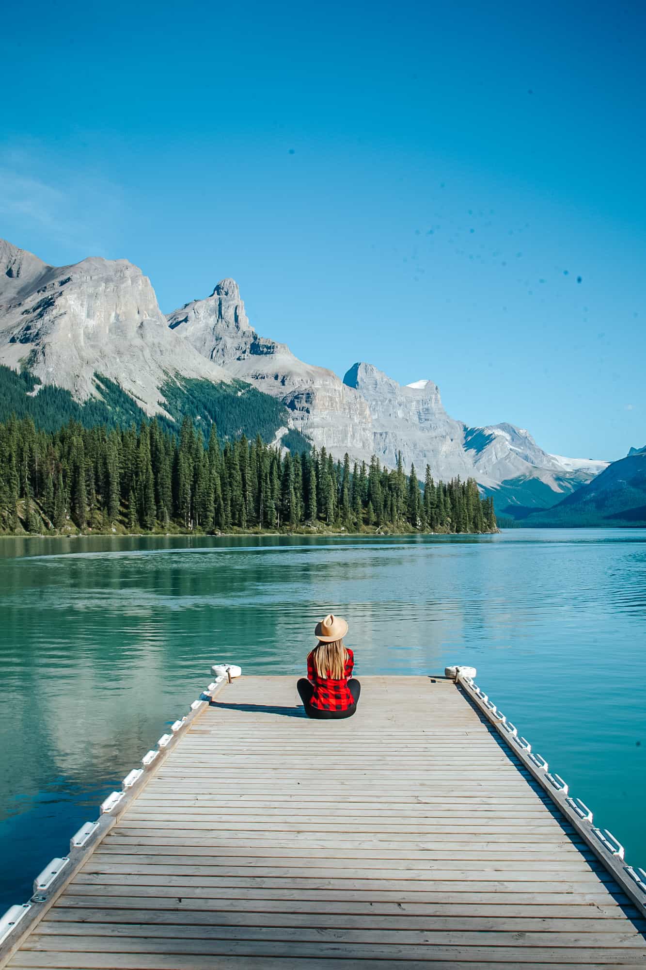 Rachael sitting on a dock at Maligne Lake looking out towards the mountains. 