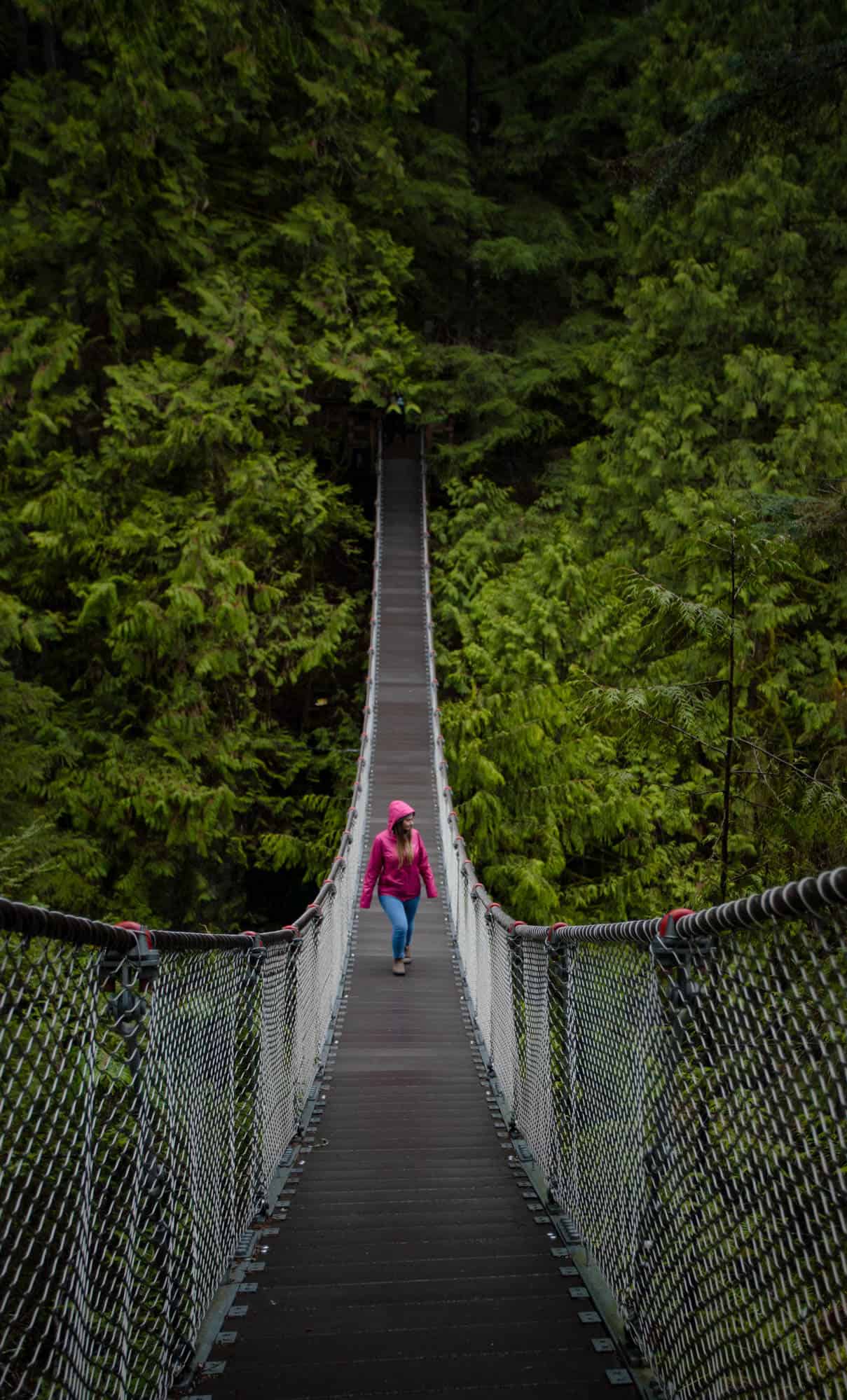 Rachael walking along the Lynn Canyon suspension bridge surrounded by lush green forest.