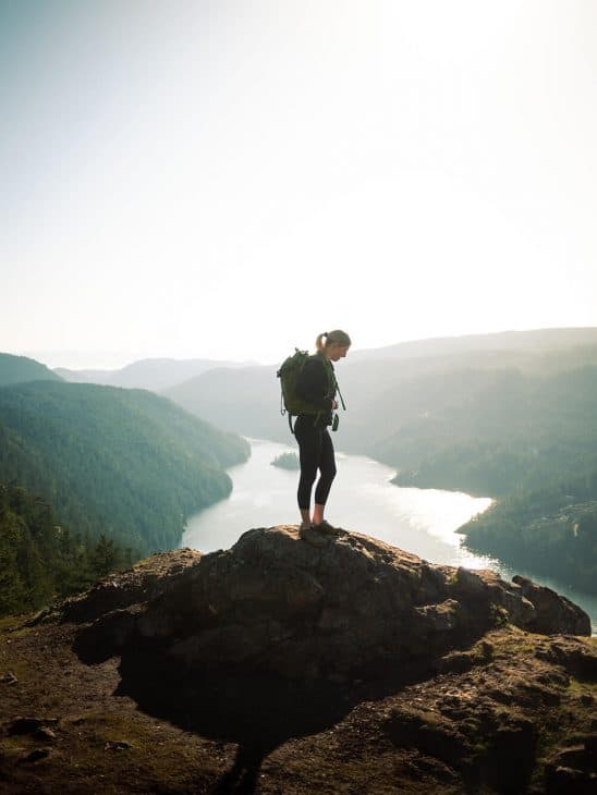 Photo of a female hiker with a fjord in the background. The Jocelyn Hill hike is an intermediate hike near Victoria. 