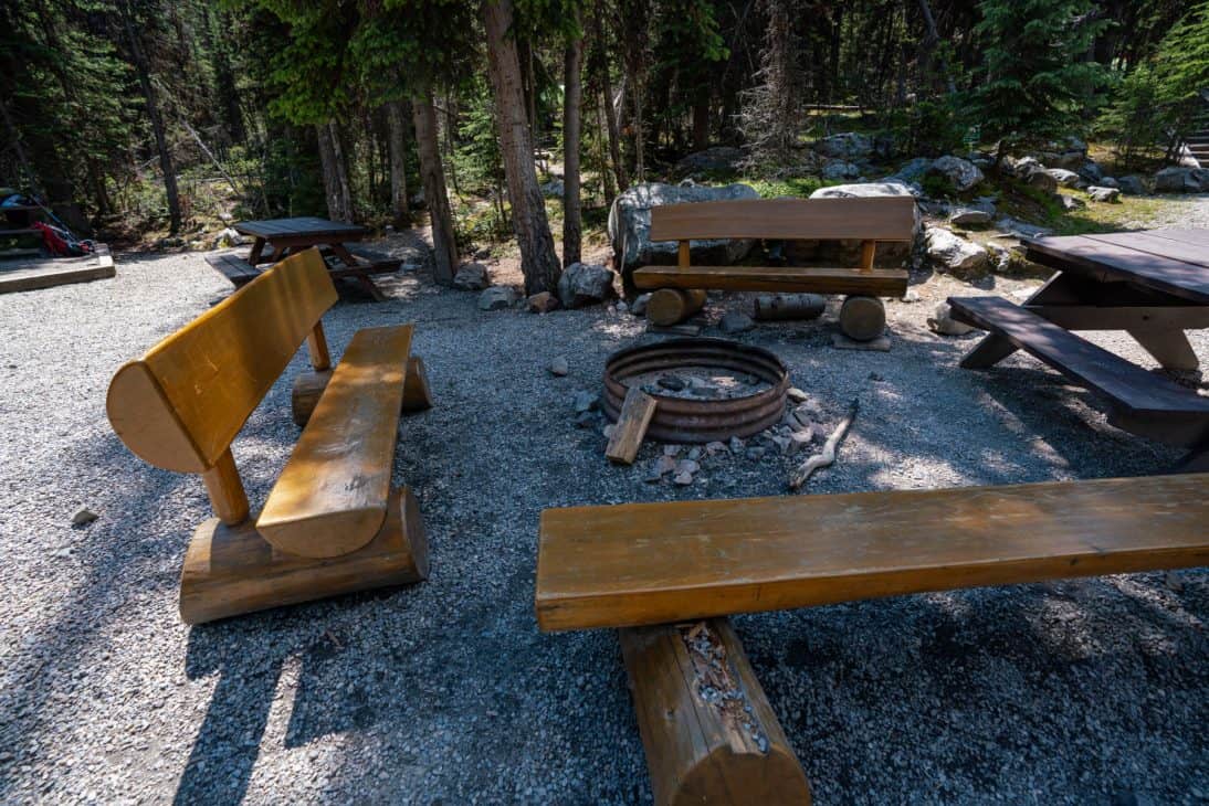 Photo of a communal fire pit surrounded by wooden benches at Lake O'Hara campground.