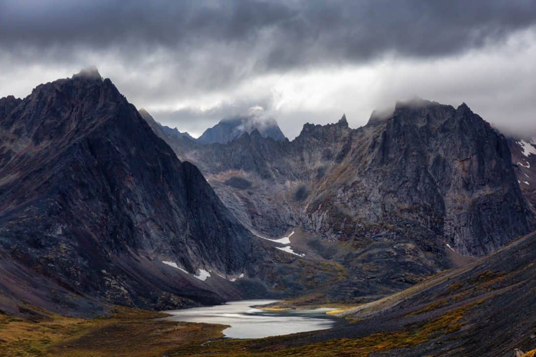 Photo of a sweeping valley surrounded by high rocky grey coloured mountains.