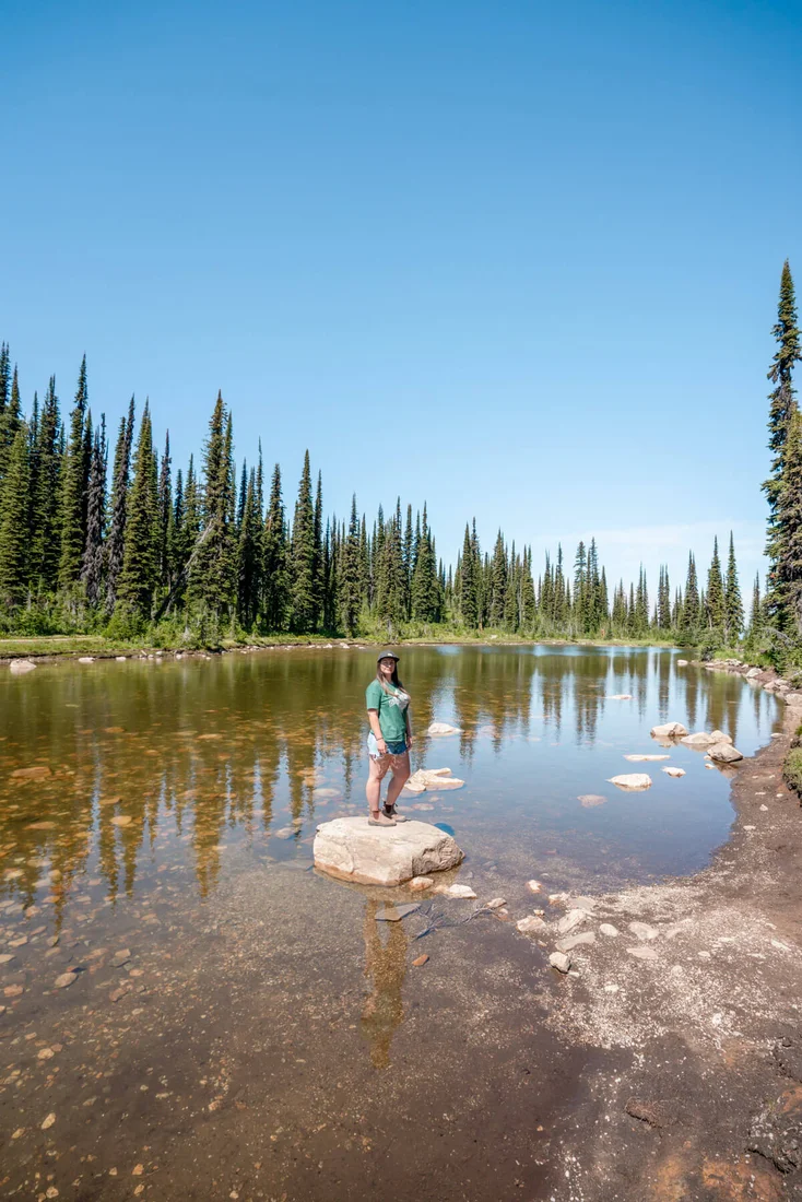 Standing on a rock in the middle of Balsam Lake near the summit of Mount Revelstoke. The Meadows in the Sky Parkway is one of the top things to do in Revelstoke.